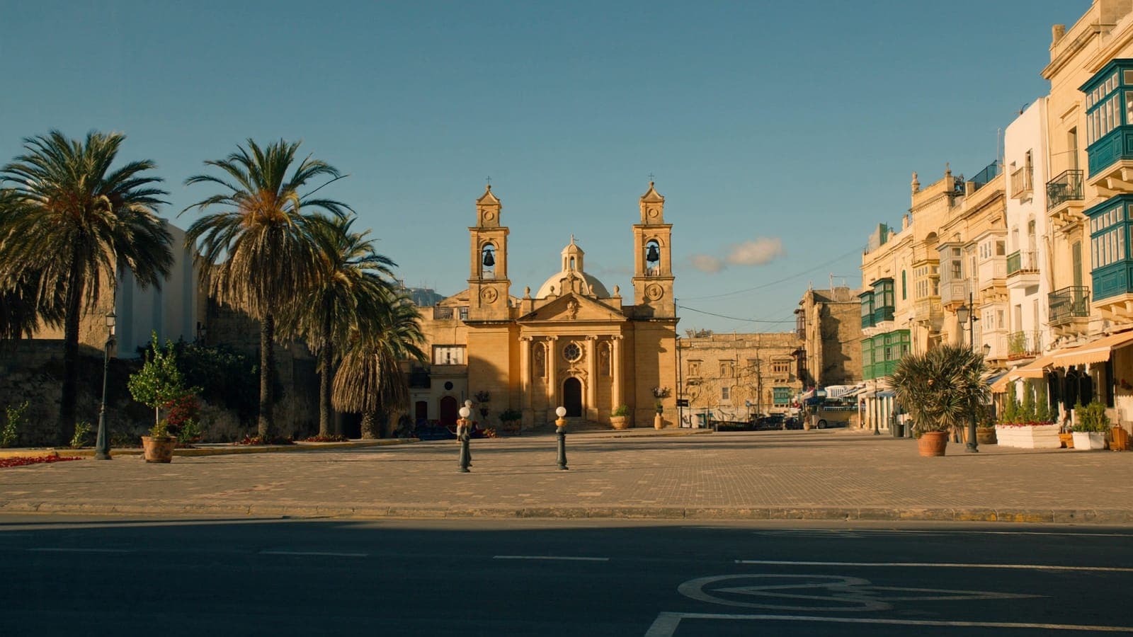 A peaceful Maltese village square with its parish church at golden hour