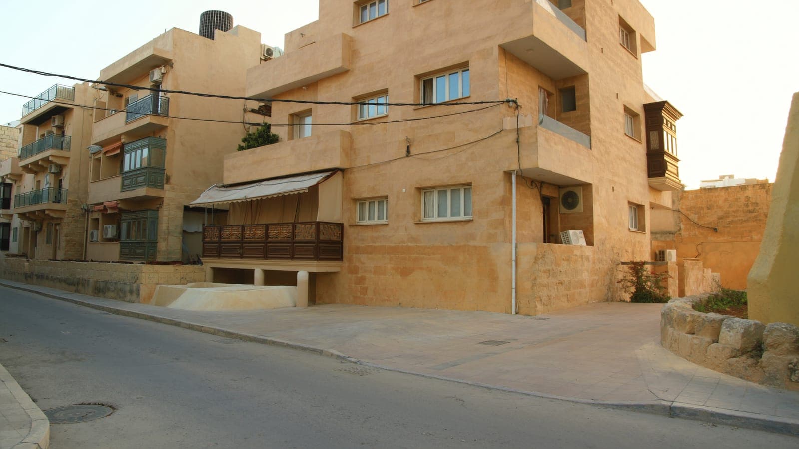 A quiet residential street in a Maltese town at golden hour
